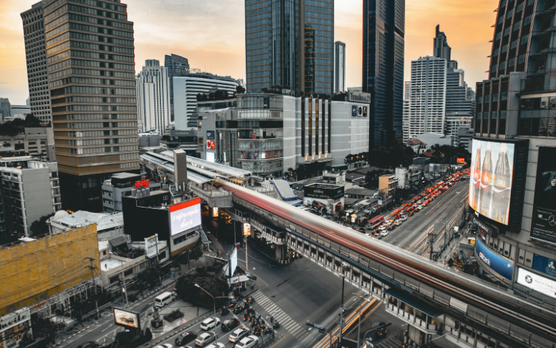A dimly lit city view with buildings and a subway train passing by.